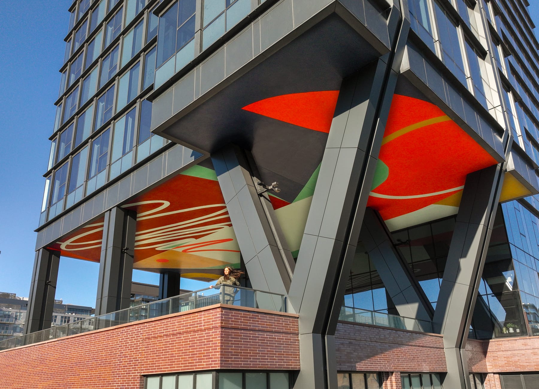 a colorful, abstract mural by Emmy Star Brown on the underside of a high-rise building's raised platform