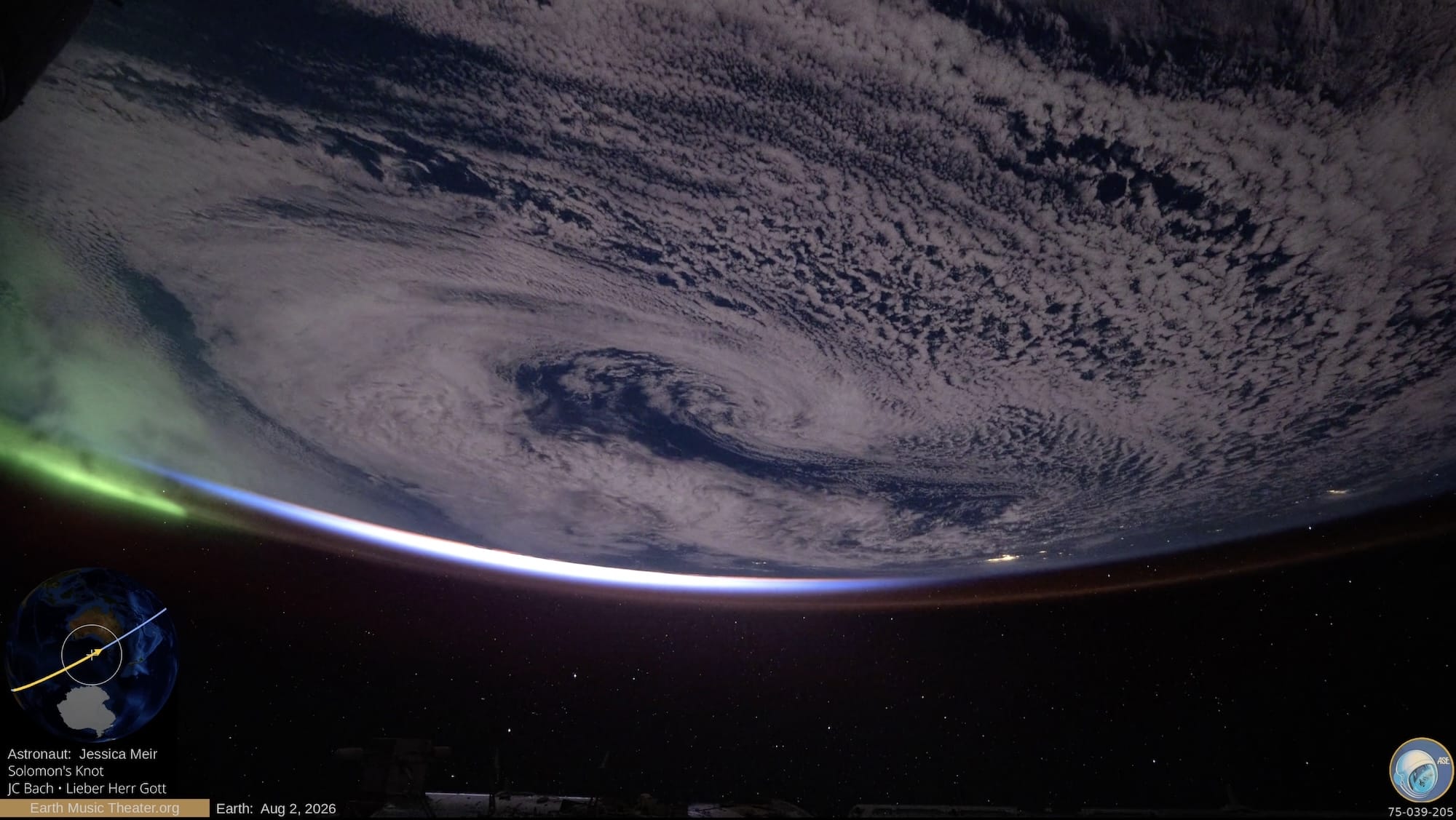 a still from a video shot from space of Earth with green aurora australis moving through the atmosphere and the halo of the sun emerging around the edge