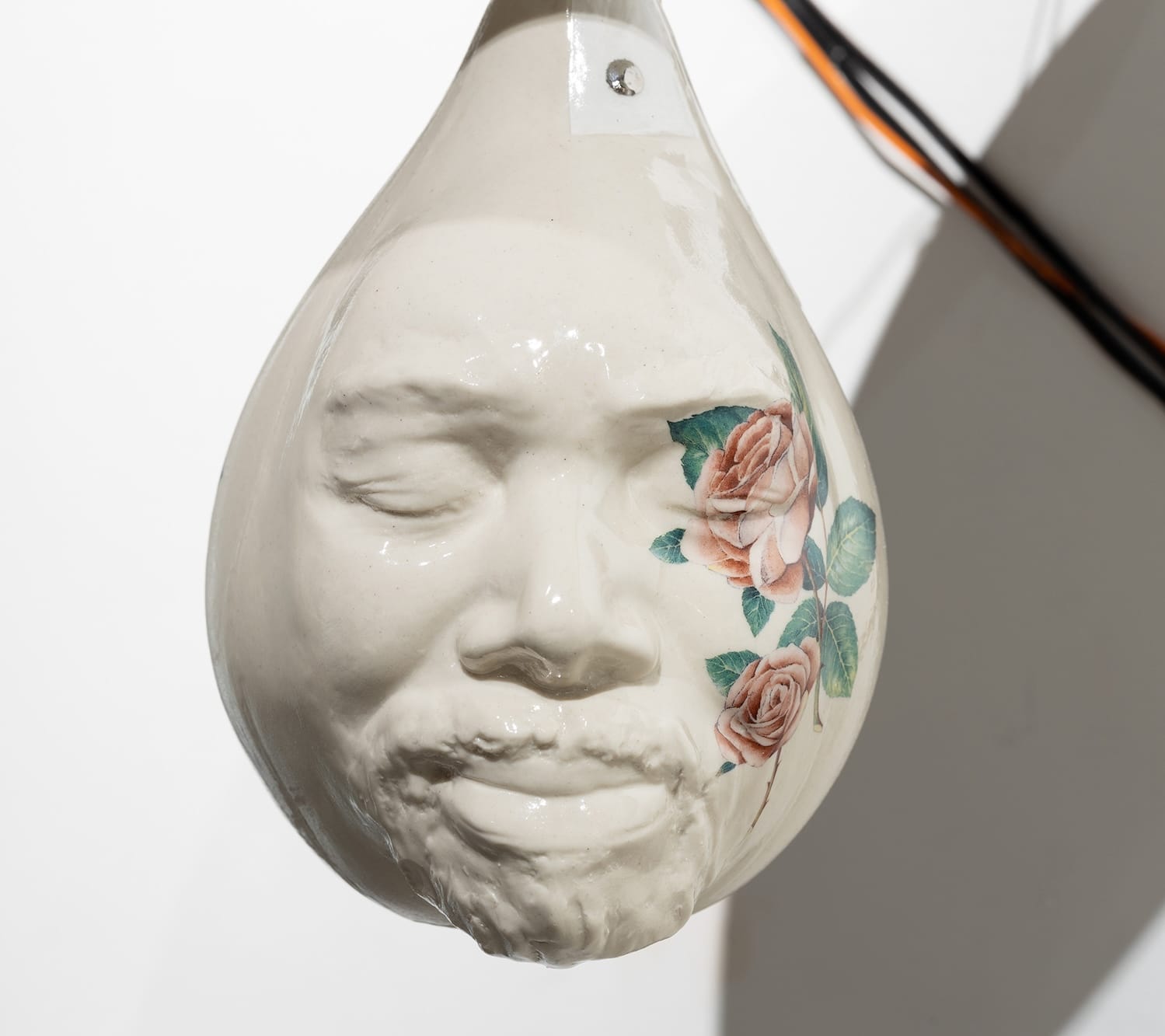 a ceramic punching bag sculpture with a face and flowers on the bag