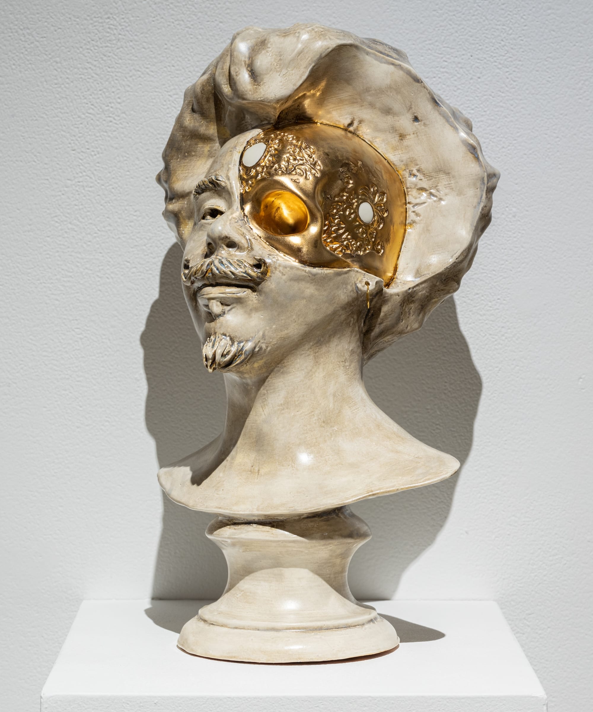 a sculptural bust of a Black man in ceramic that looks like alabaster, with a part of the face replaced with a cyborg detail