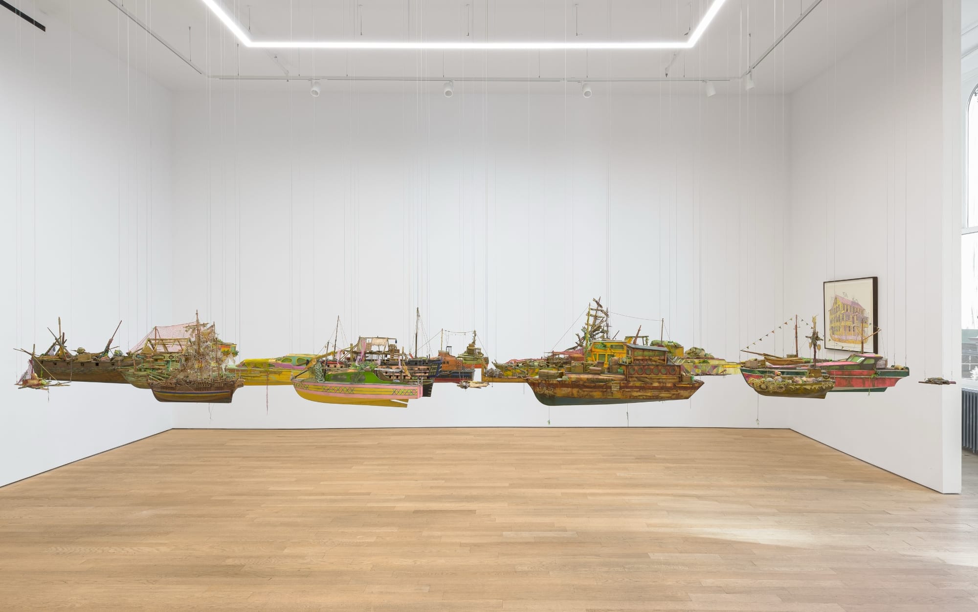 a suspended flotilla of Hew Locke's ships hang in a gallery