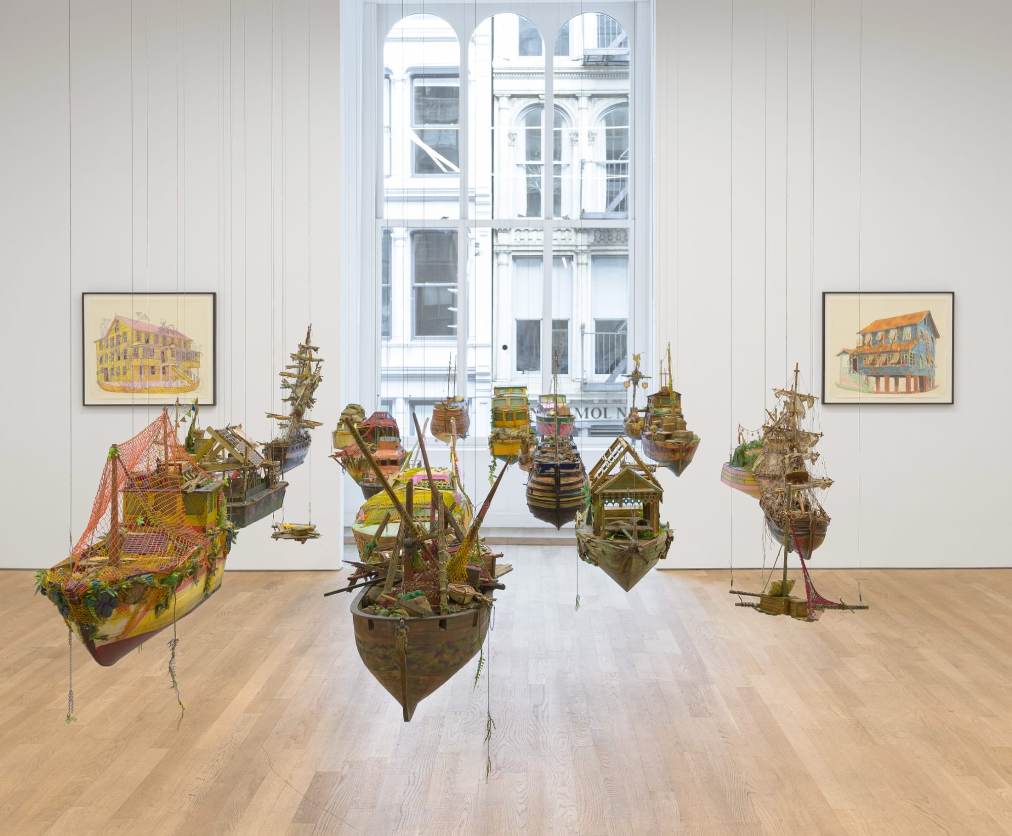 a suspended flotilla of Hew Locke's ships hang in a gallery