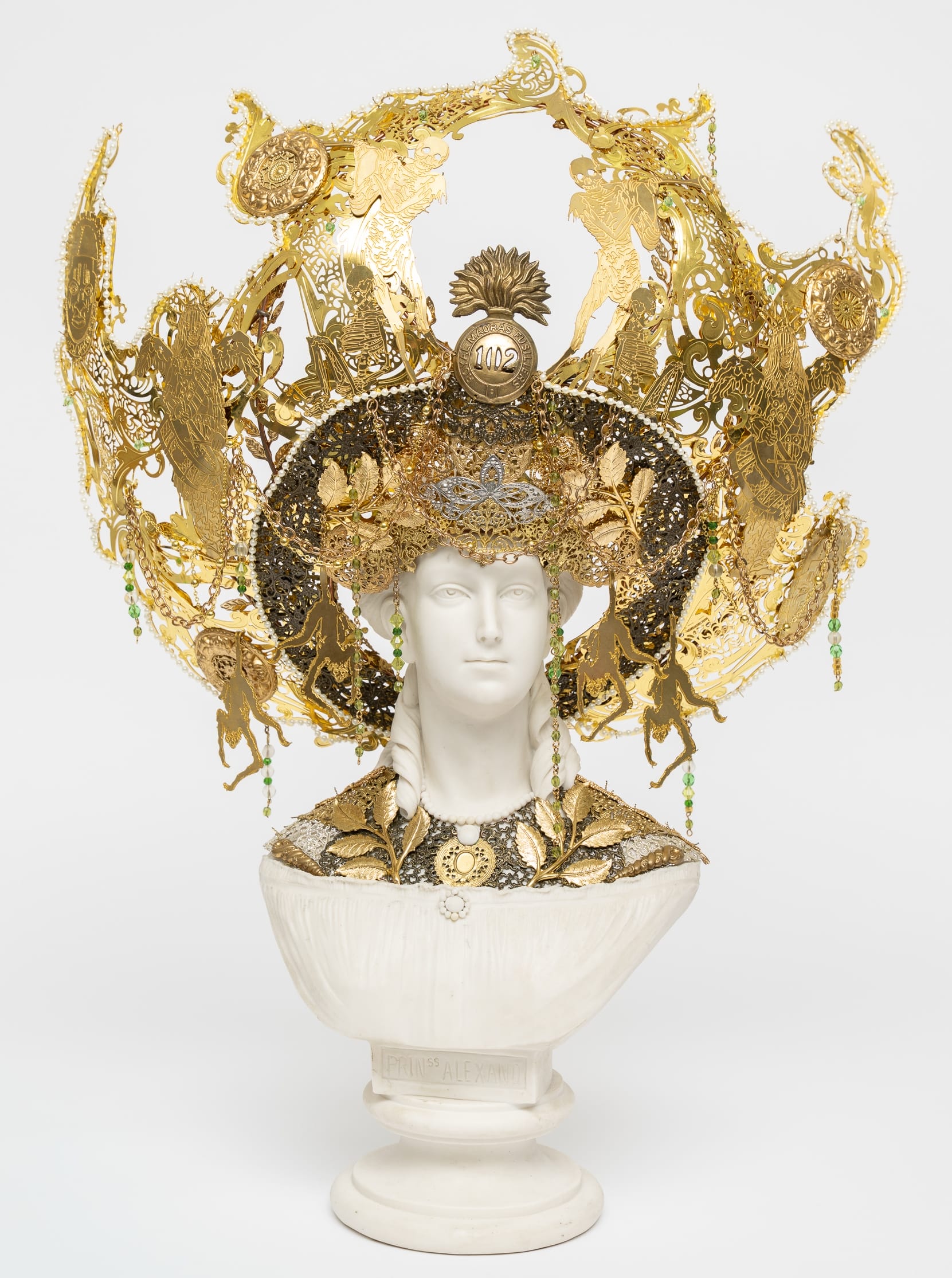 a mixed media sculpture by hew Locke of a white bust with a gold crown