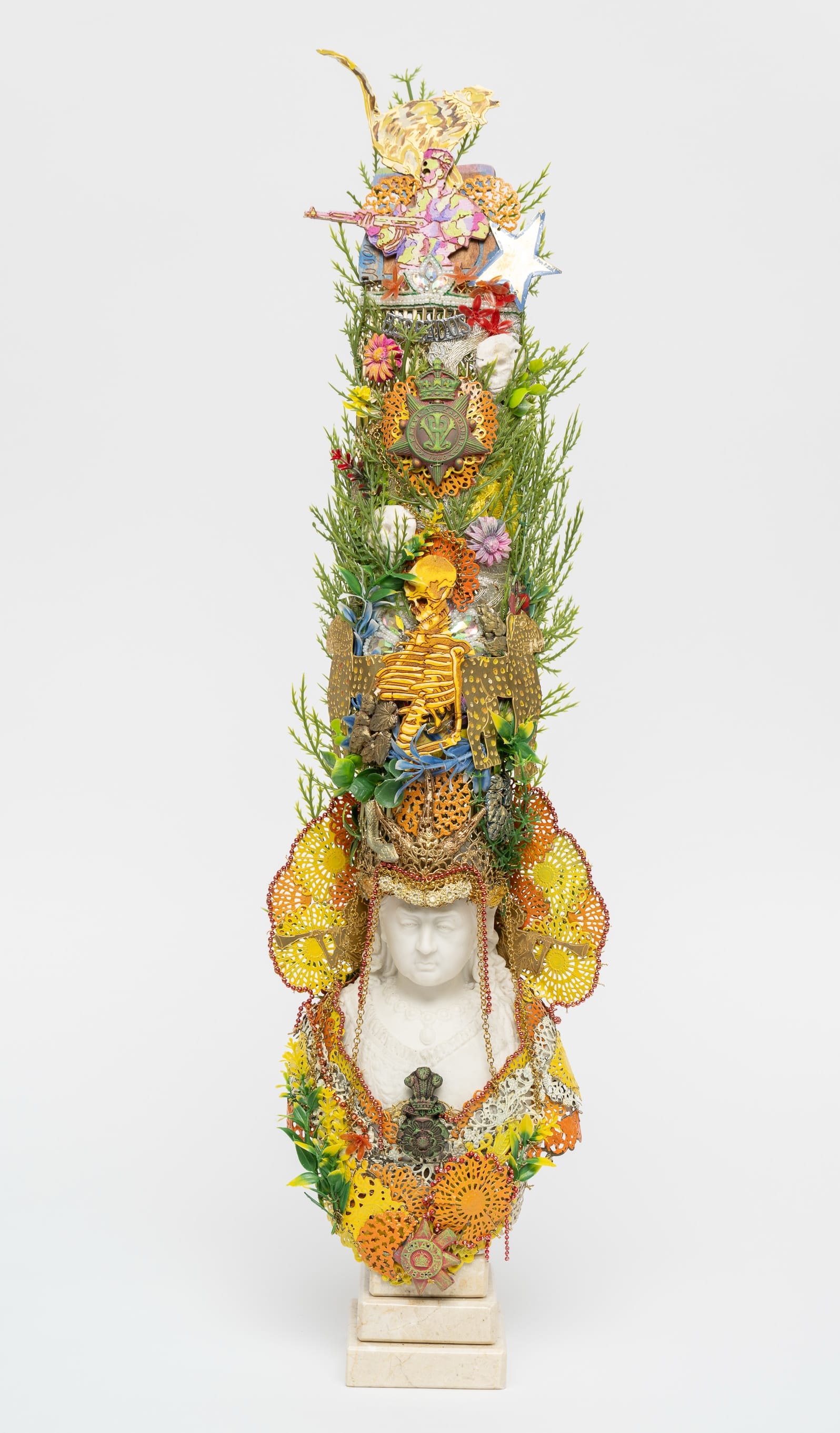 a bust sculpture by Hew Locke with a towering headdress of foliage, a skeleton, and more