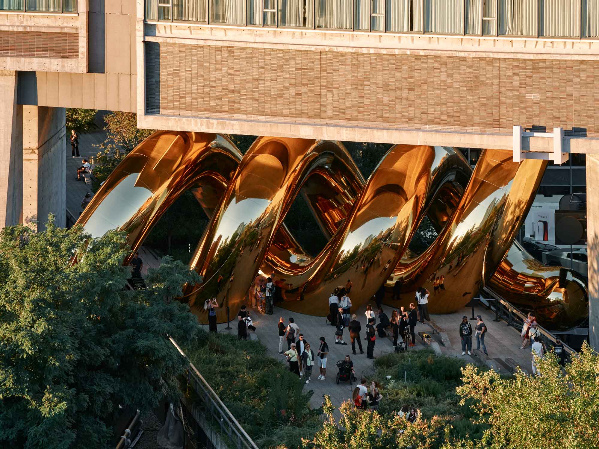 a giant inflatable sculpture of a gold spiral wedged beneath an overpass on the High Line in Manhattan