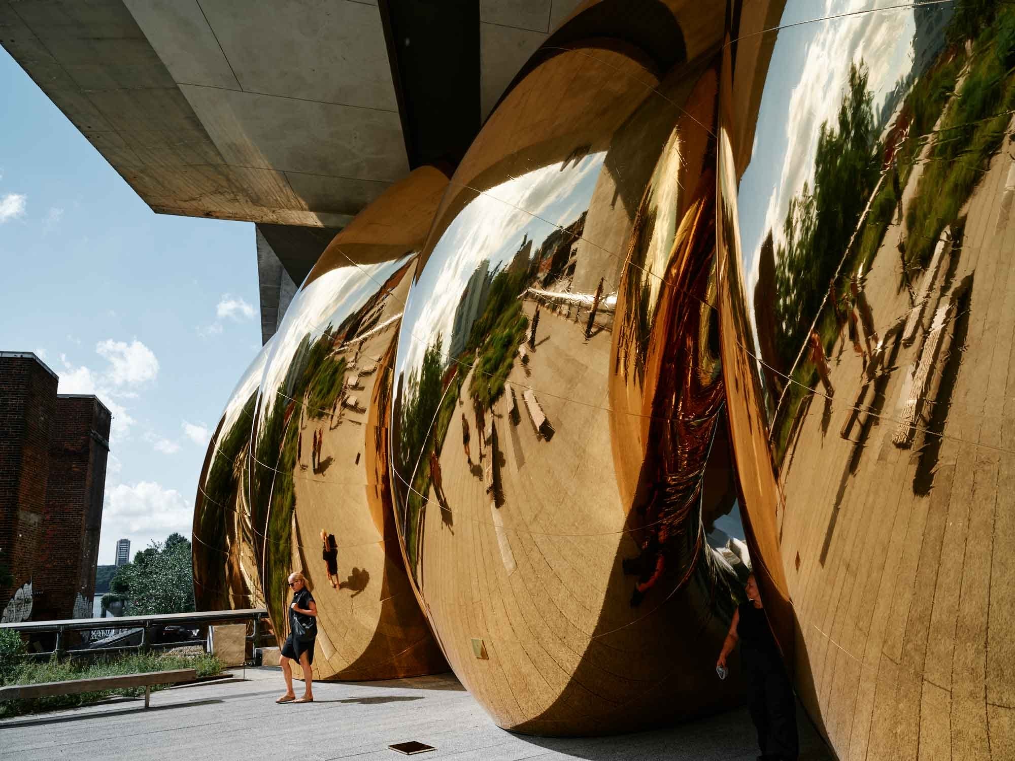 a giant inflatable sculpture of a gold spiral wedged beneath an overpass on the High Line in Manhattan