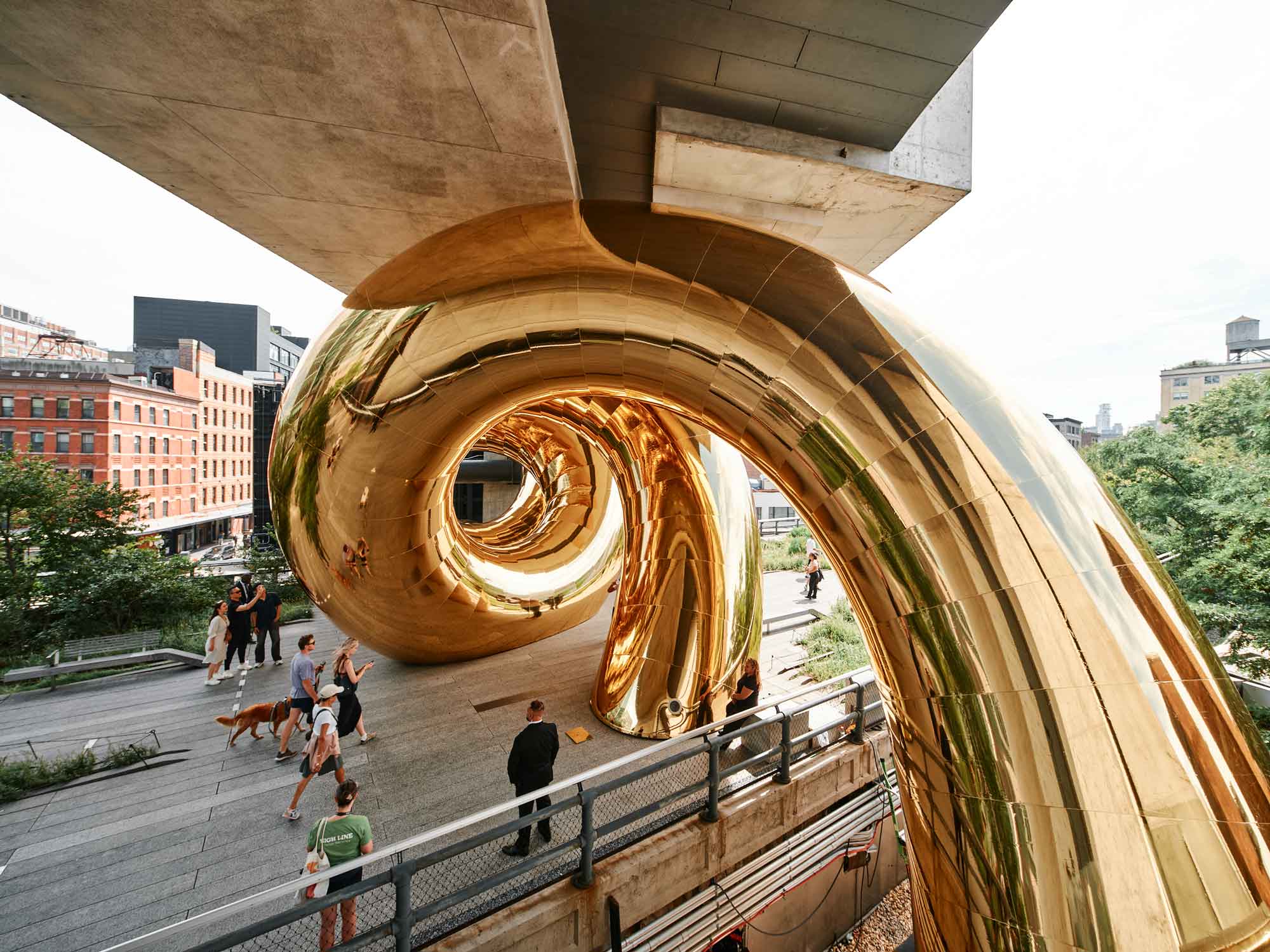 a giant inflatable sculpture of a gold spiral wedged beneath an overpass on the High Line in Manhattan