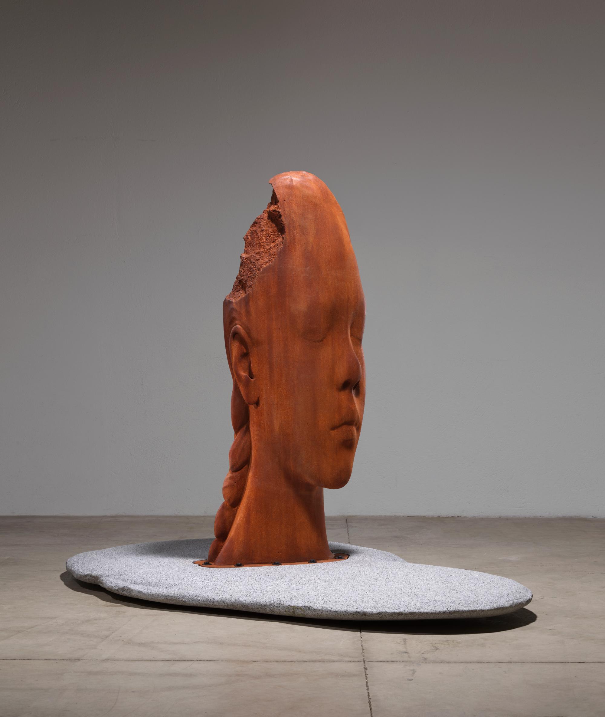 a sculpture by Jaume Plensa of a cast iron head resting upon a granite stone