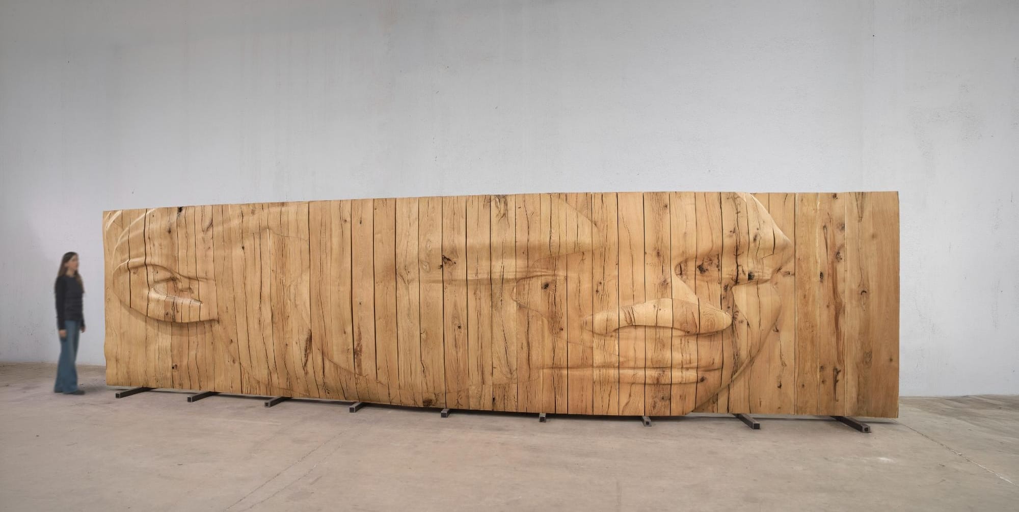 a wide wooden relief sculpture by Jaume Plensa depicting a carving of a face