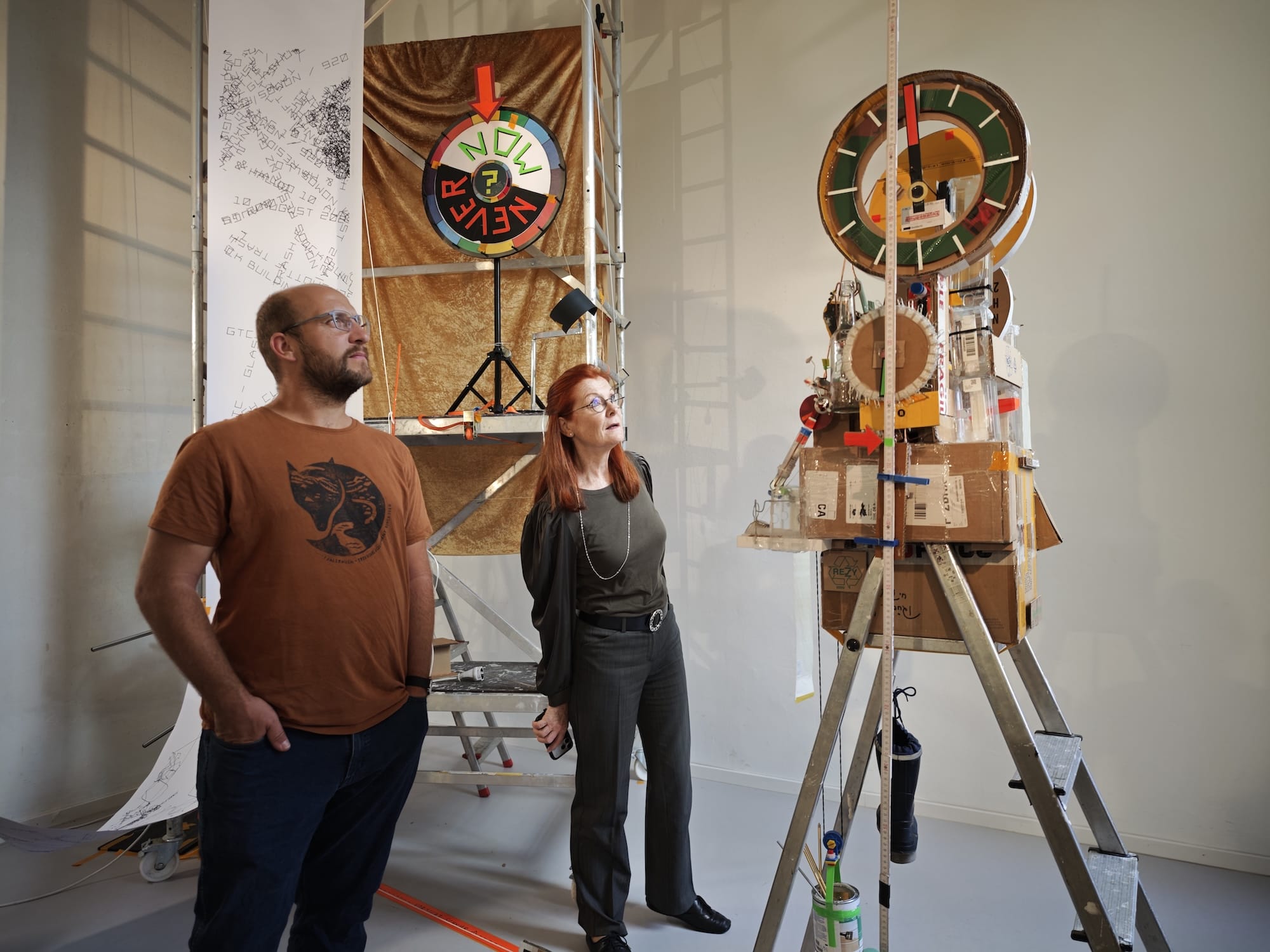 people stand next to a sculptural, functional clock made from foraged trash