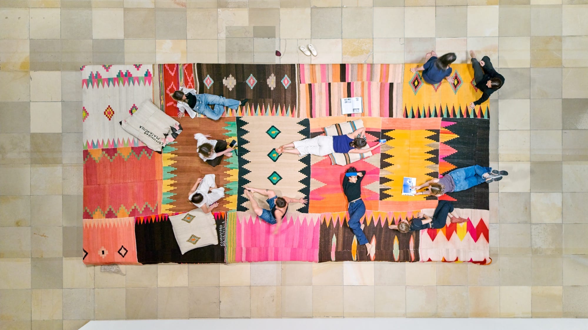 an aerial image of people on a vibrant tribal blanket