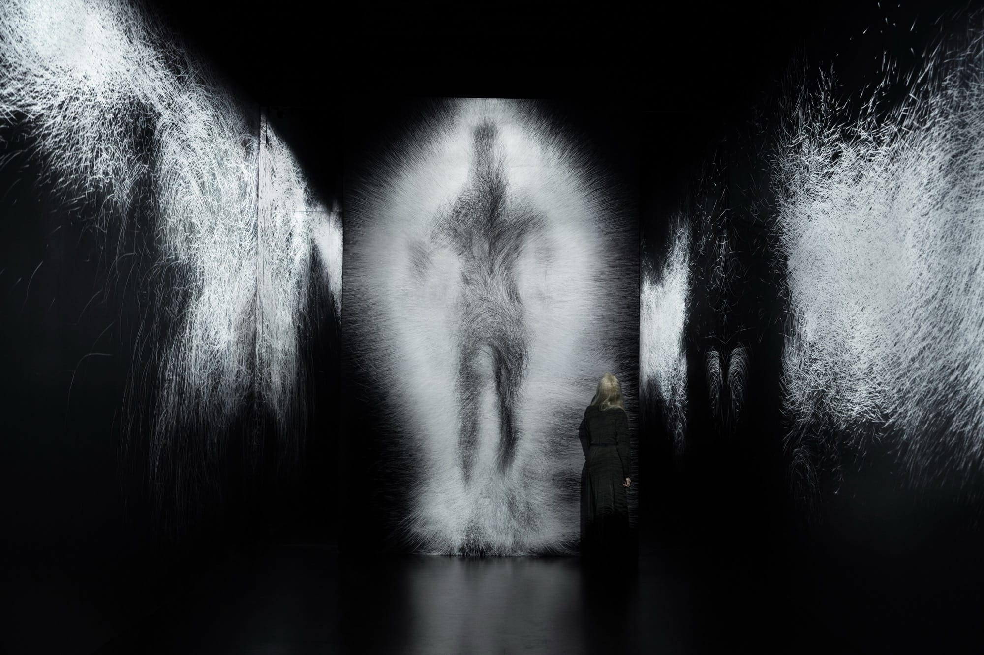 a still of a large figure in a blur of white walking through a dark room