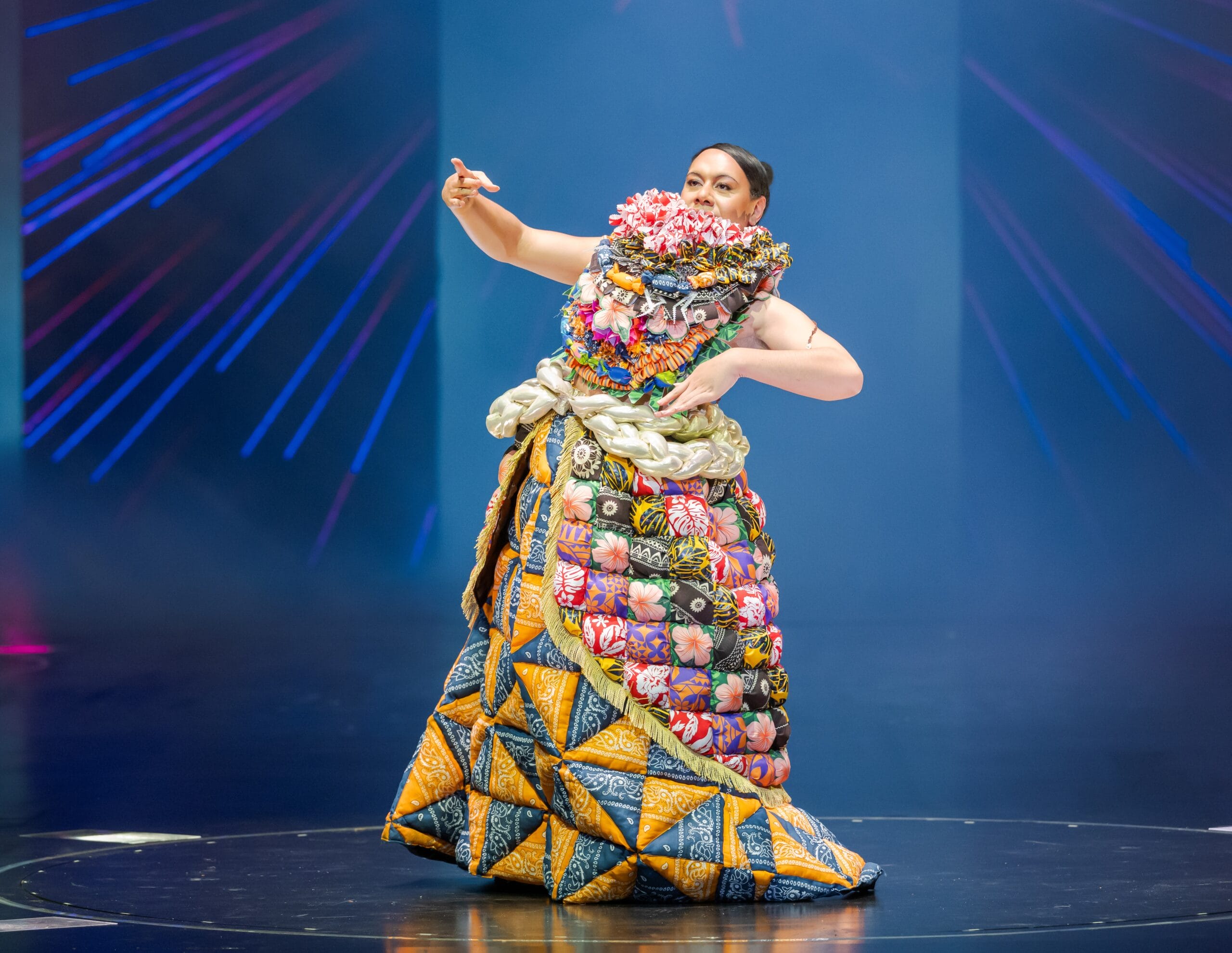 an elaborate handmade gown being demonstrated on stage, with elements that look like giant, geometrically folded candy wrappers