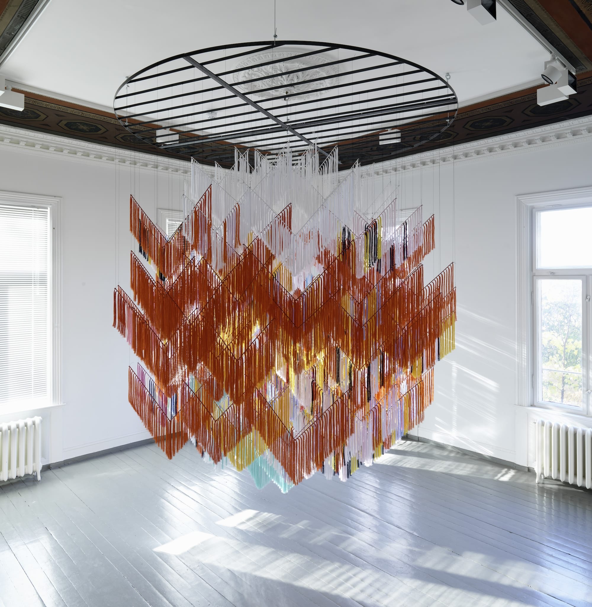 an interior art installation suspended from the ceiling to create a red, geometric form that "floats" in the middle of the room