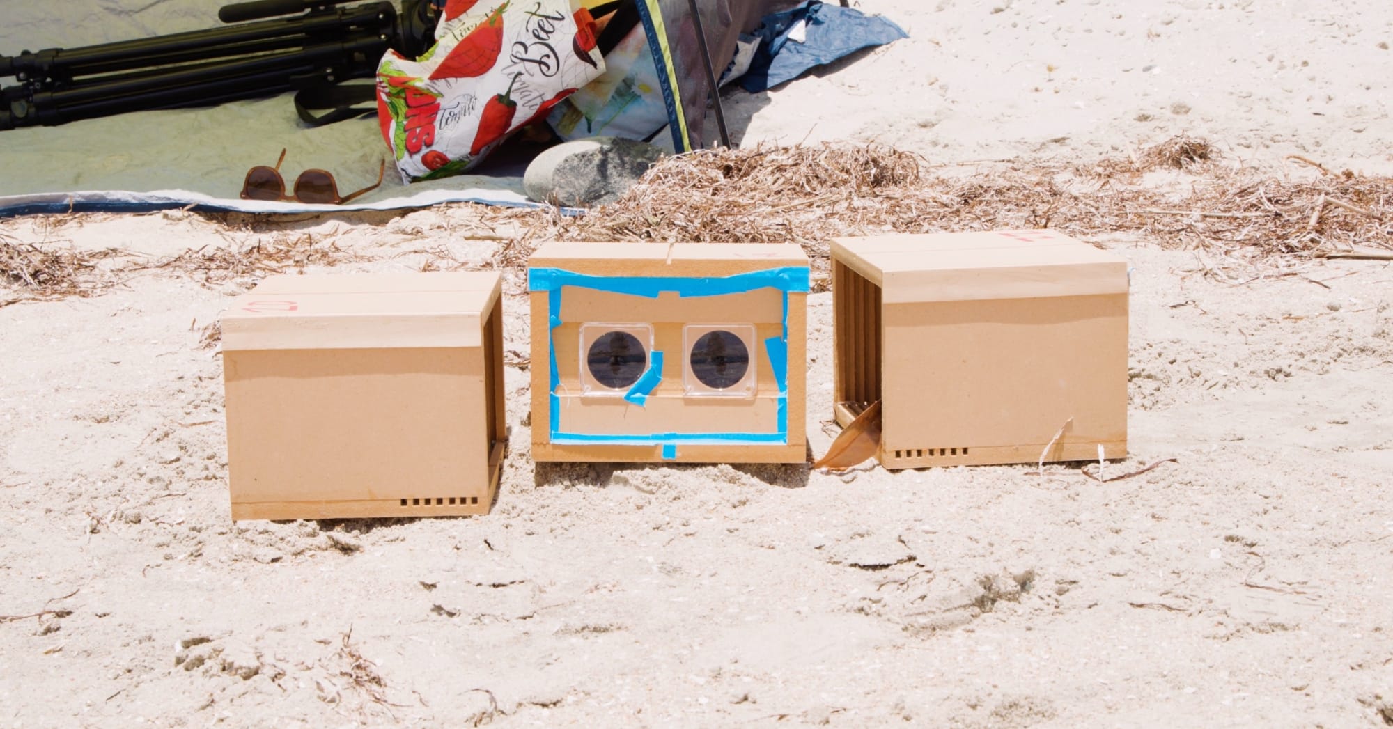 a still of three cardboard box cameras on sand