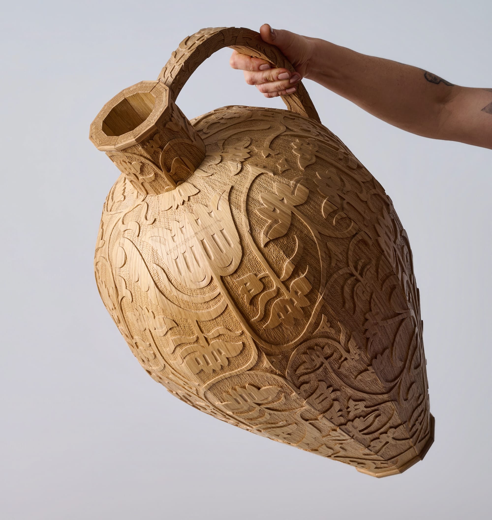 a wooden jug with a large handle and intricate hand-carved designs around the outside