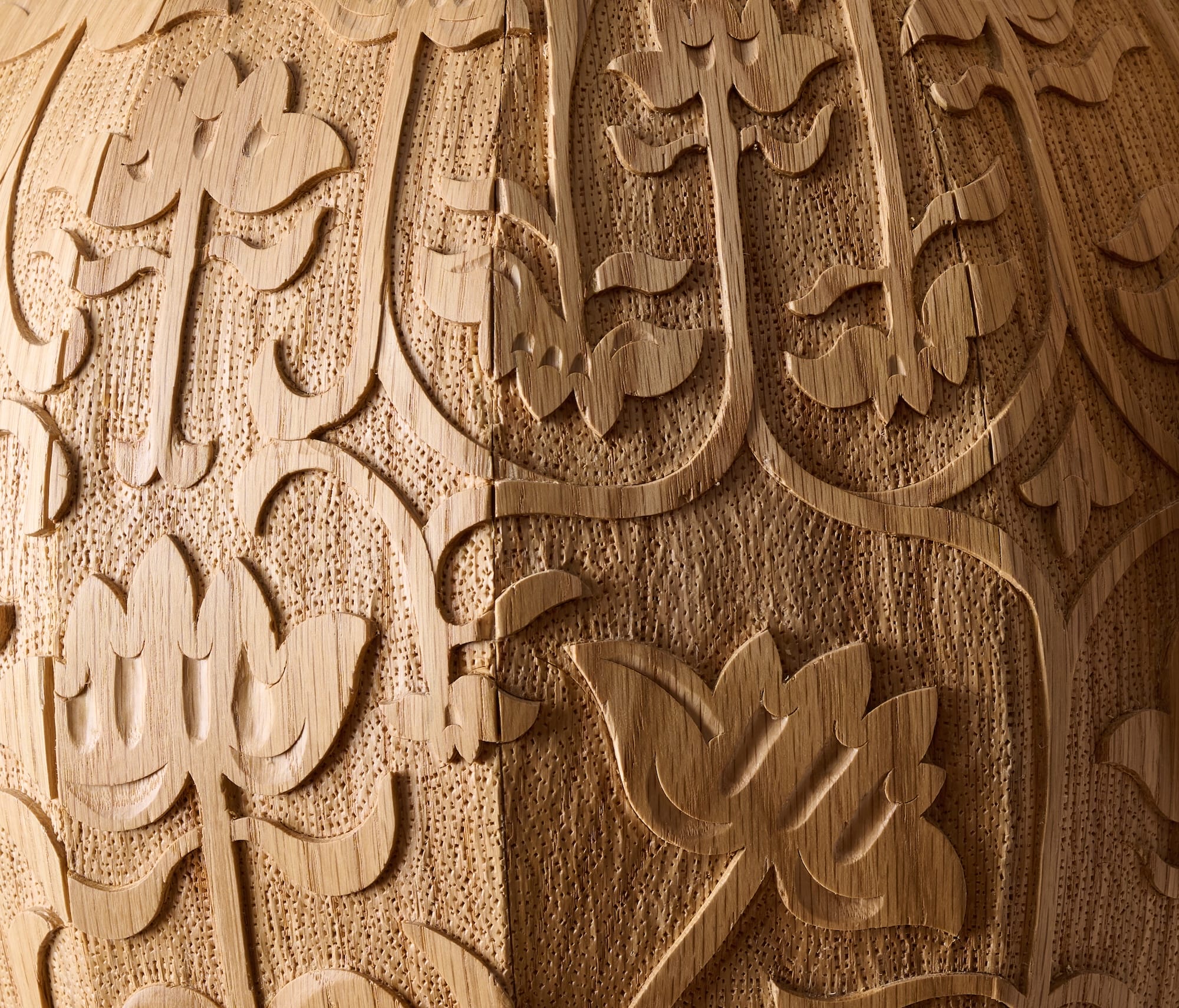 a detail of a wooden jug's intricate hand-carved designs around the outside