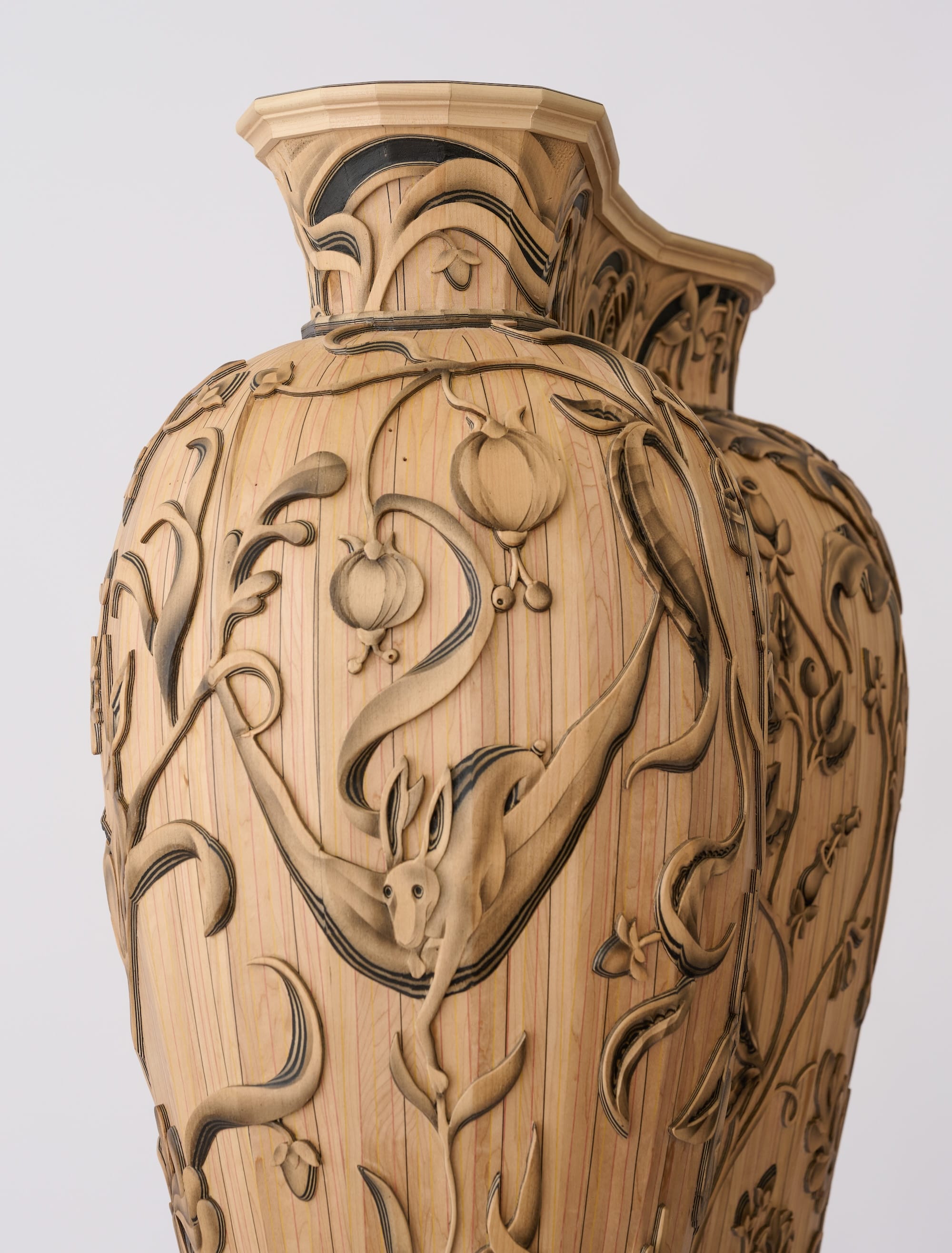 a large wooden cabinet that resembles a giant vessel, with crewel-inspired wood carving on the exterior featuring plants and animals