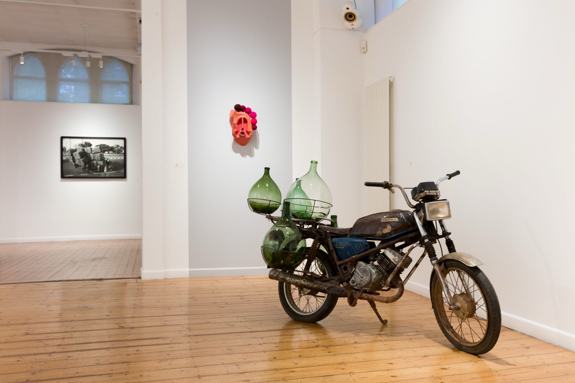 a white walled gallery with a sculpture on the wall and a motorcycle parked nearby