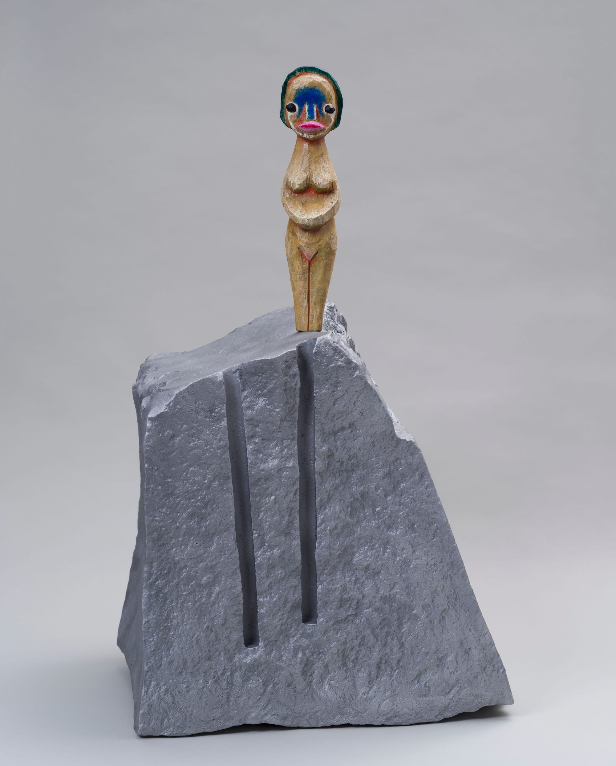 a small sculpture by Izumi Kato of a surreal figure standing on top of a boulder