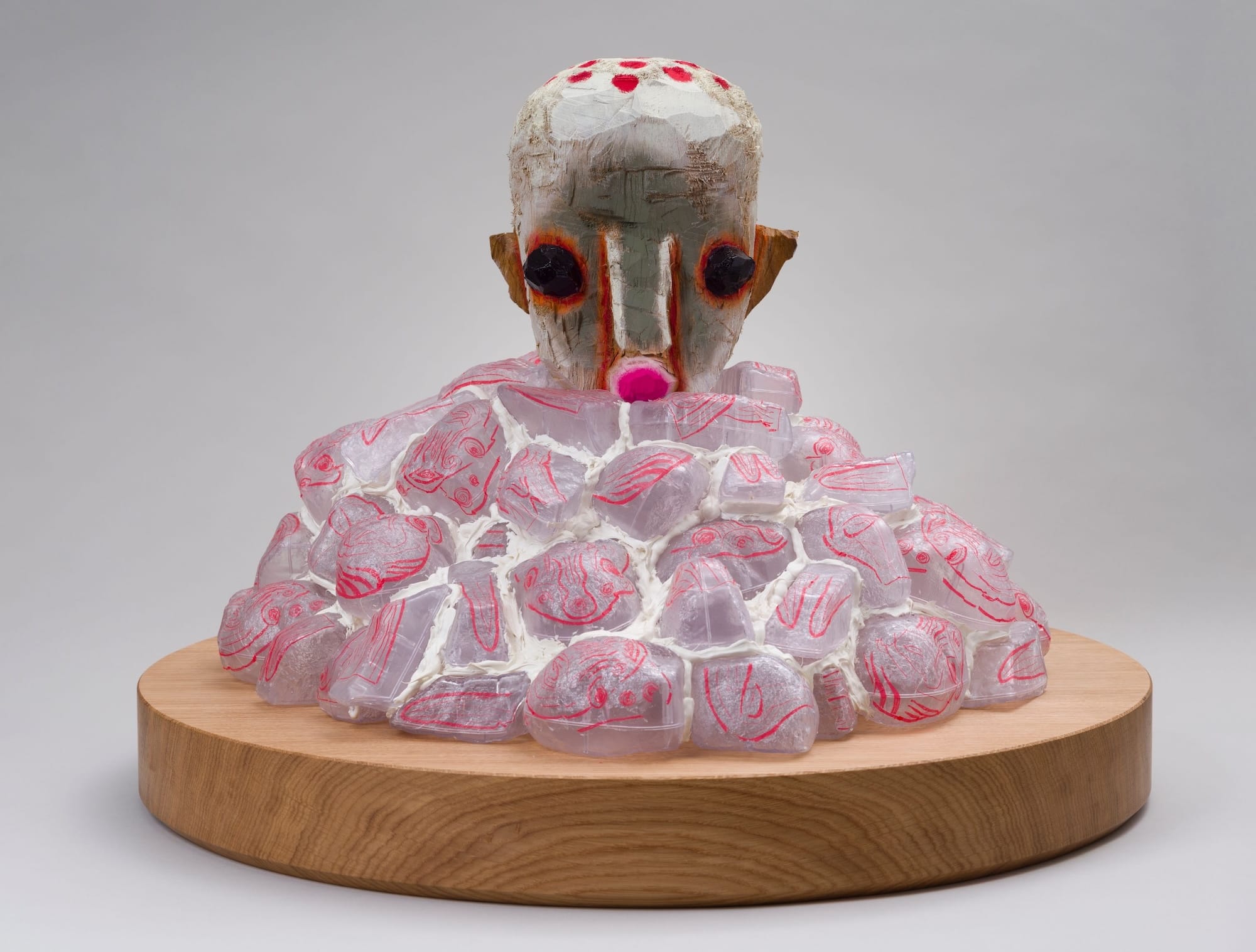 a small sculpture by Izumi Kato of a surreal figure's head peeking out from a nebulous pink pile