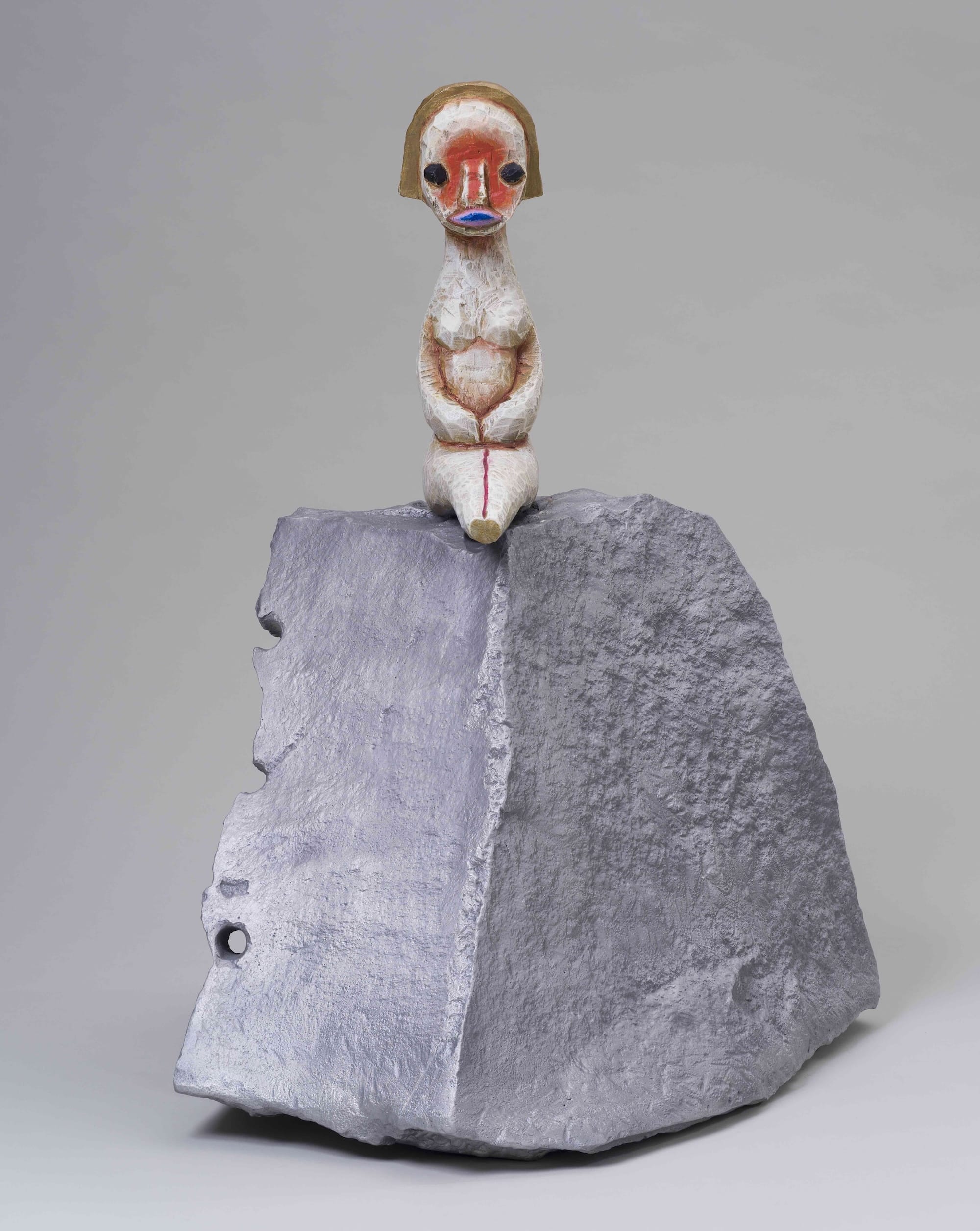 a small sculpture by Izumi Kato of a surreal figure seated on top of a boulder