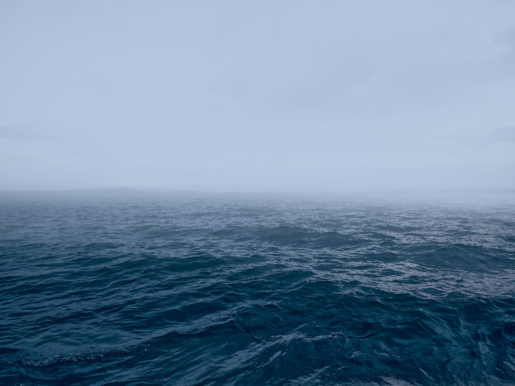 an open body of water with fog in the distance