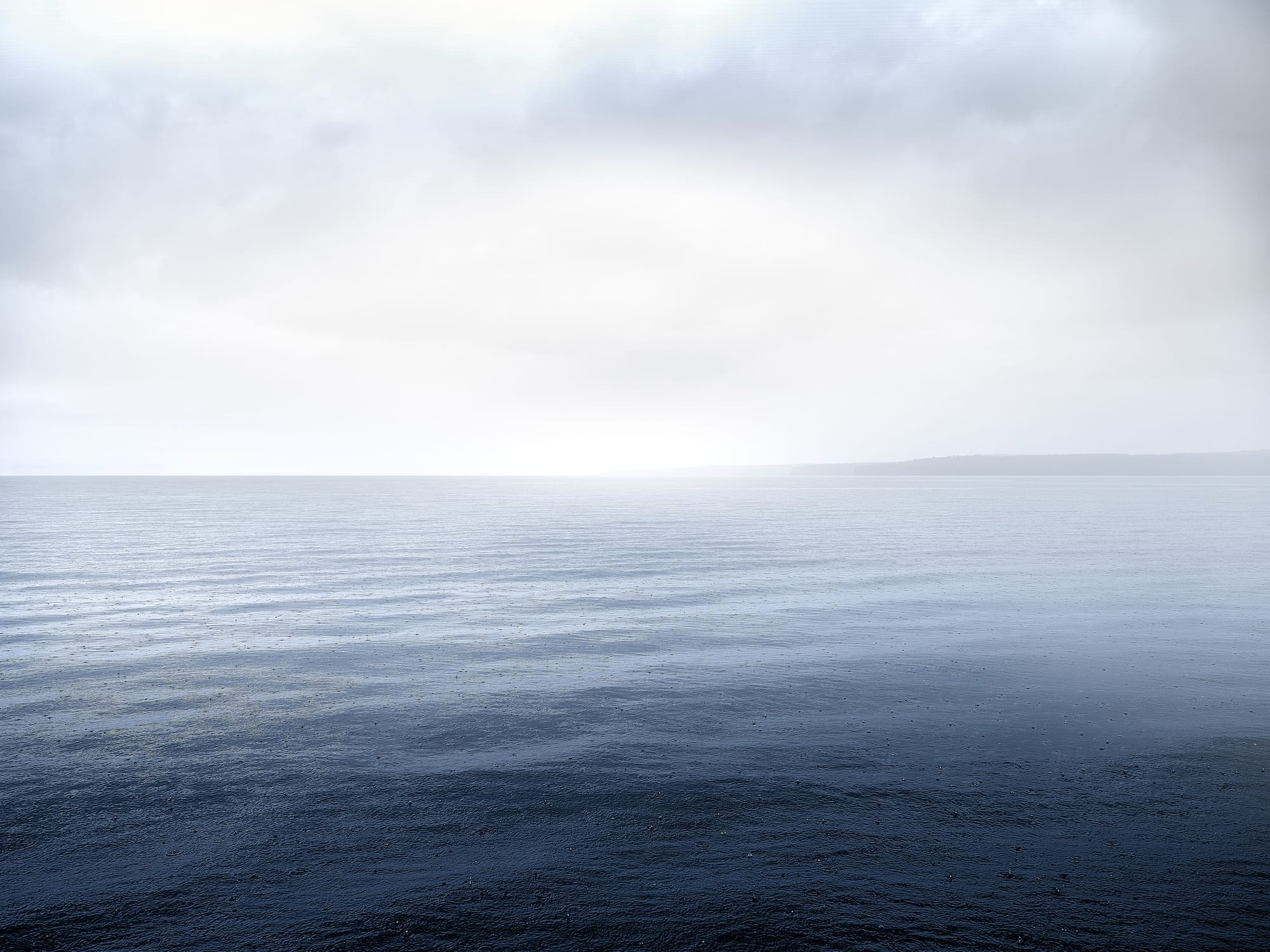 an open body of water during the early morning with light clouds in the sky
