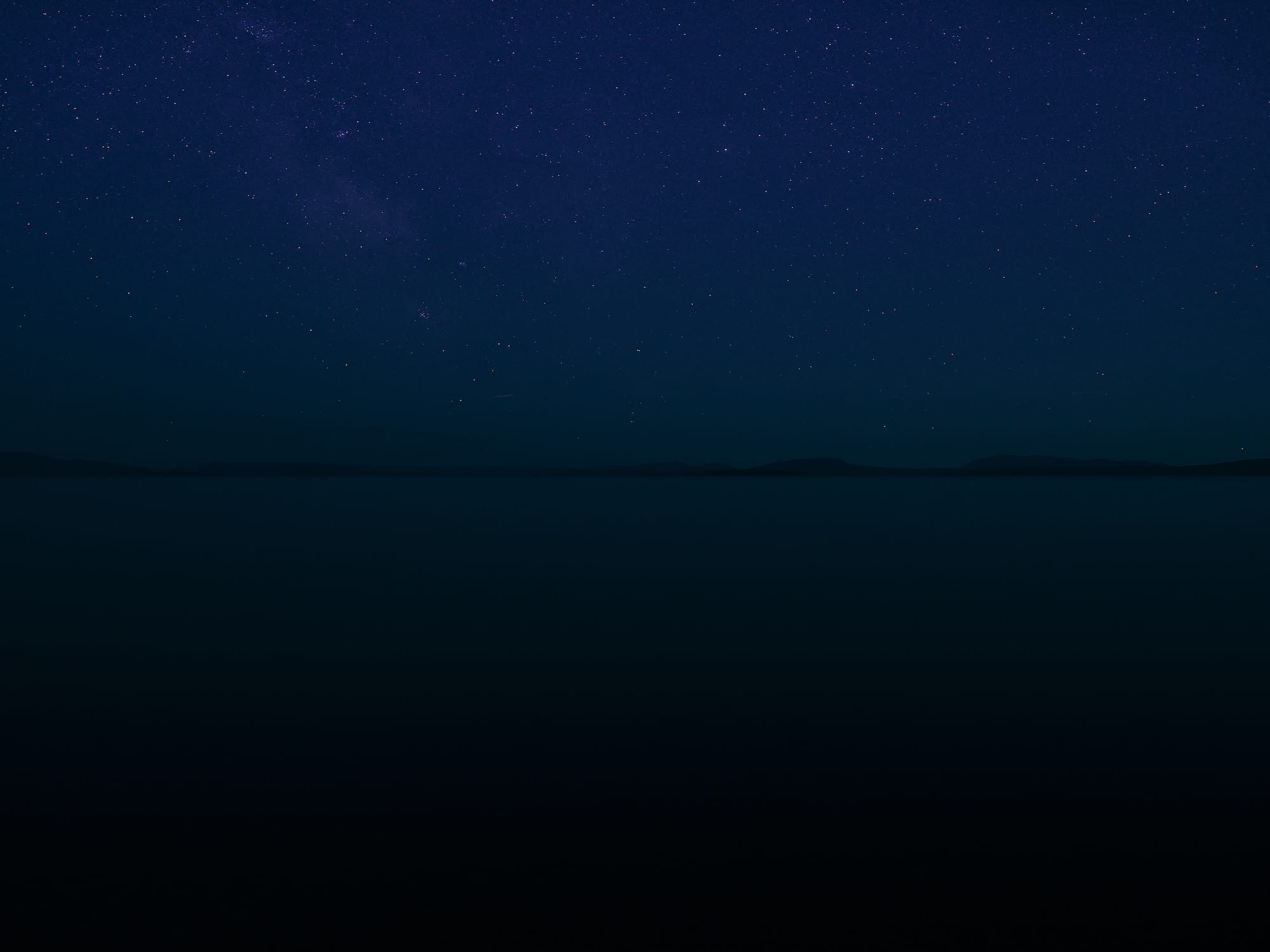 a nighttime scene on an open body of water with stars in the sky