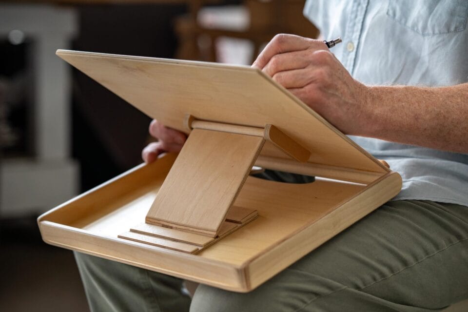 an artist working on a drawing with the assistance of a wooden lap easel made by Bill Groot
