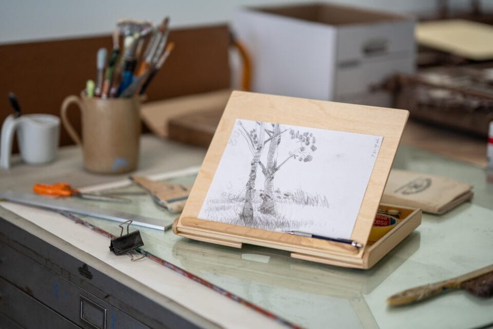 a wooden lap easel made by Bill Groot holds a drawing on its surface
