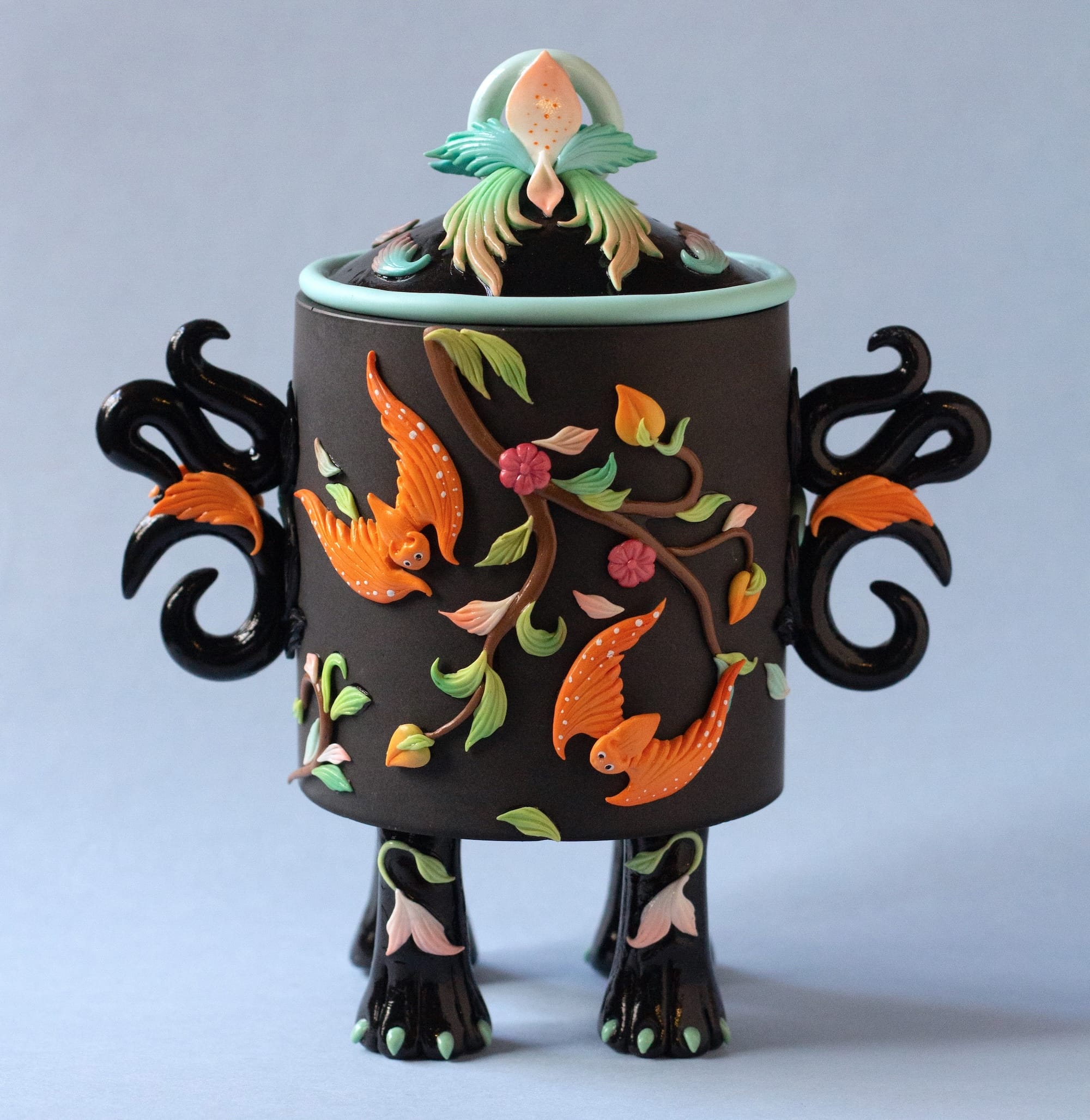 a stylized snuff bottle sculpture made from polymer clay featuring a relief of peach branches and orange bats