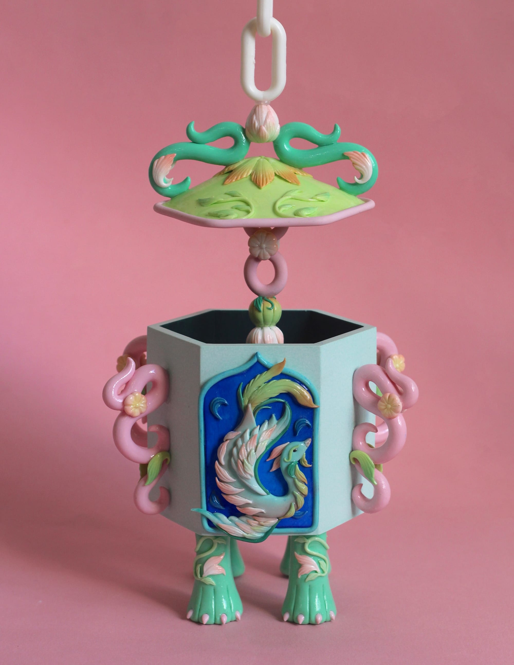 a stylized snuff bottle sculpture made from polymer clay featuring a relief of a phoenix-like bird