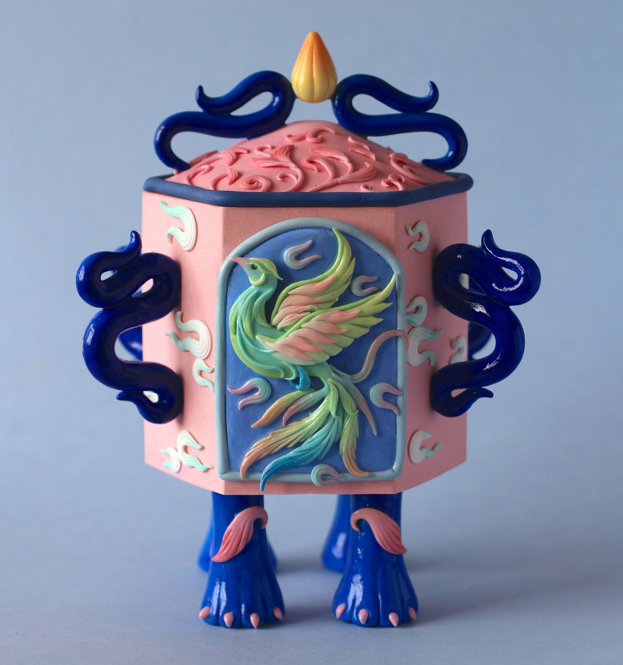 a stylized snuff bottle sculpture made from polymer clay featuring a relief of a phoenix