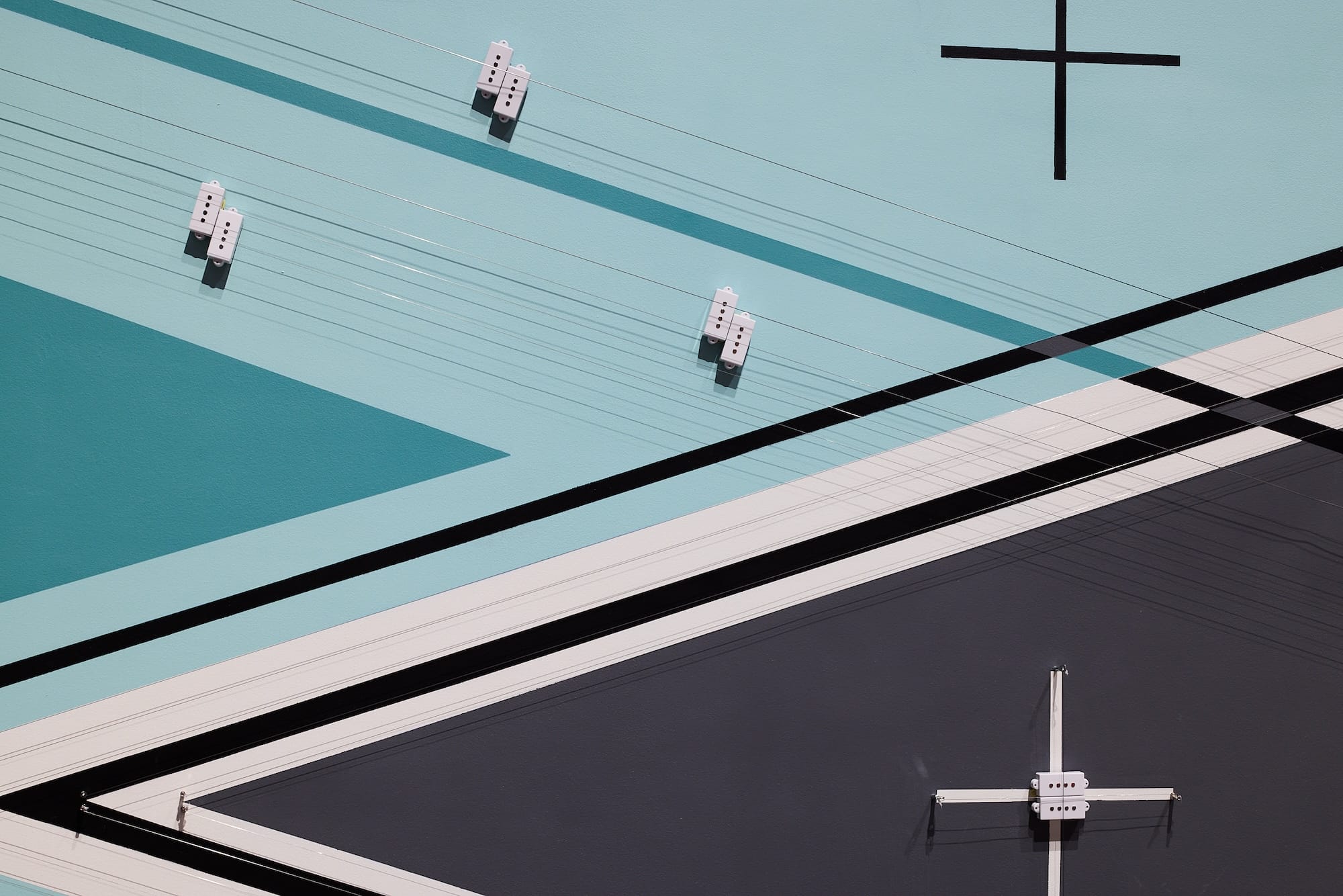 a detail of an abstract geometric installation with strings that produce sound on a light blue and black background
