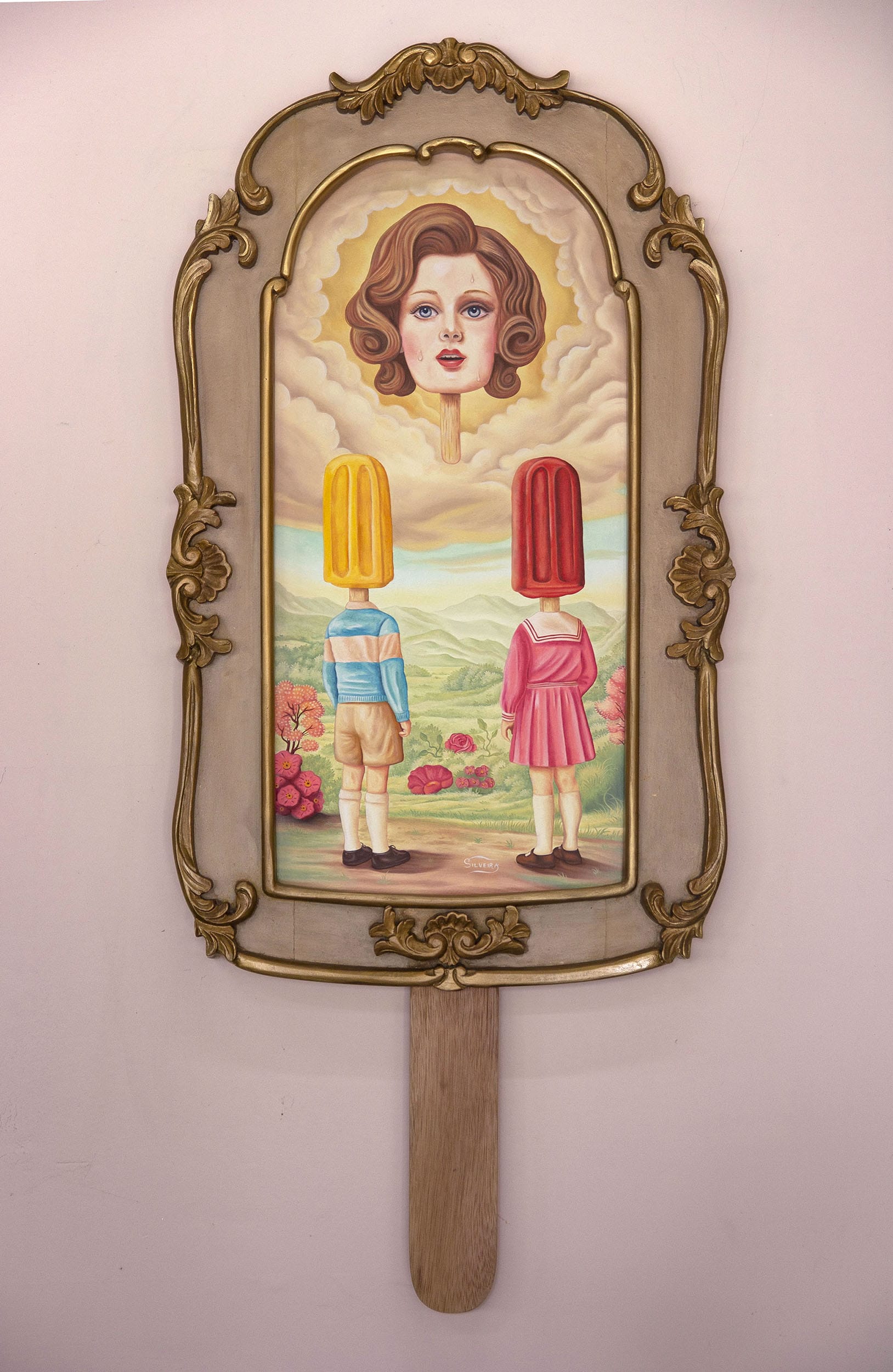 a vertical painting in a hand-carved wooden frame shaped like a popsicle with an image of a woman in the sky, like a deity, overlooking two children with popsicles for heads
