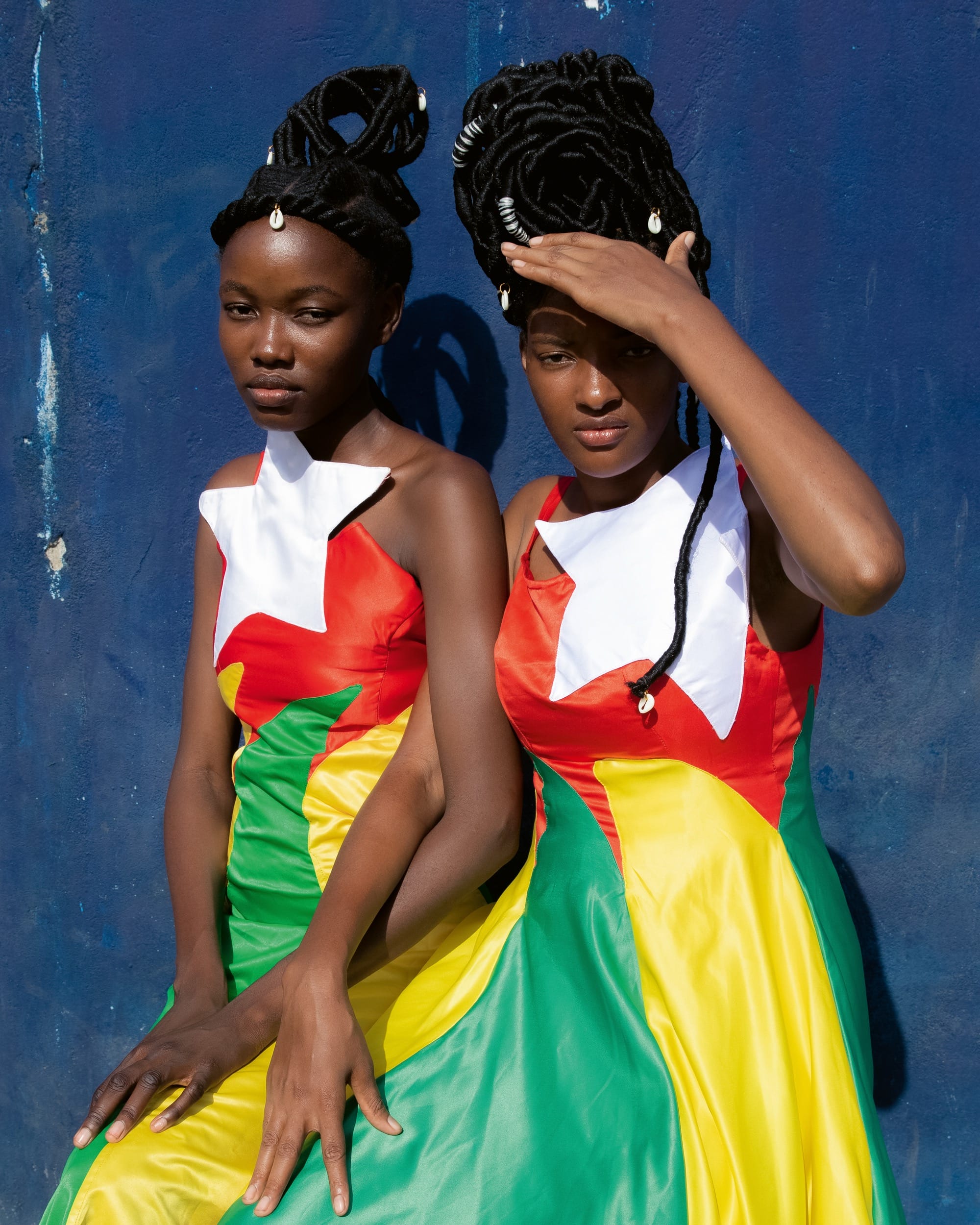 a portrait of two teen girls in matching dresses. one shields her eyes