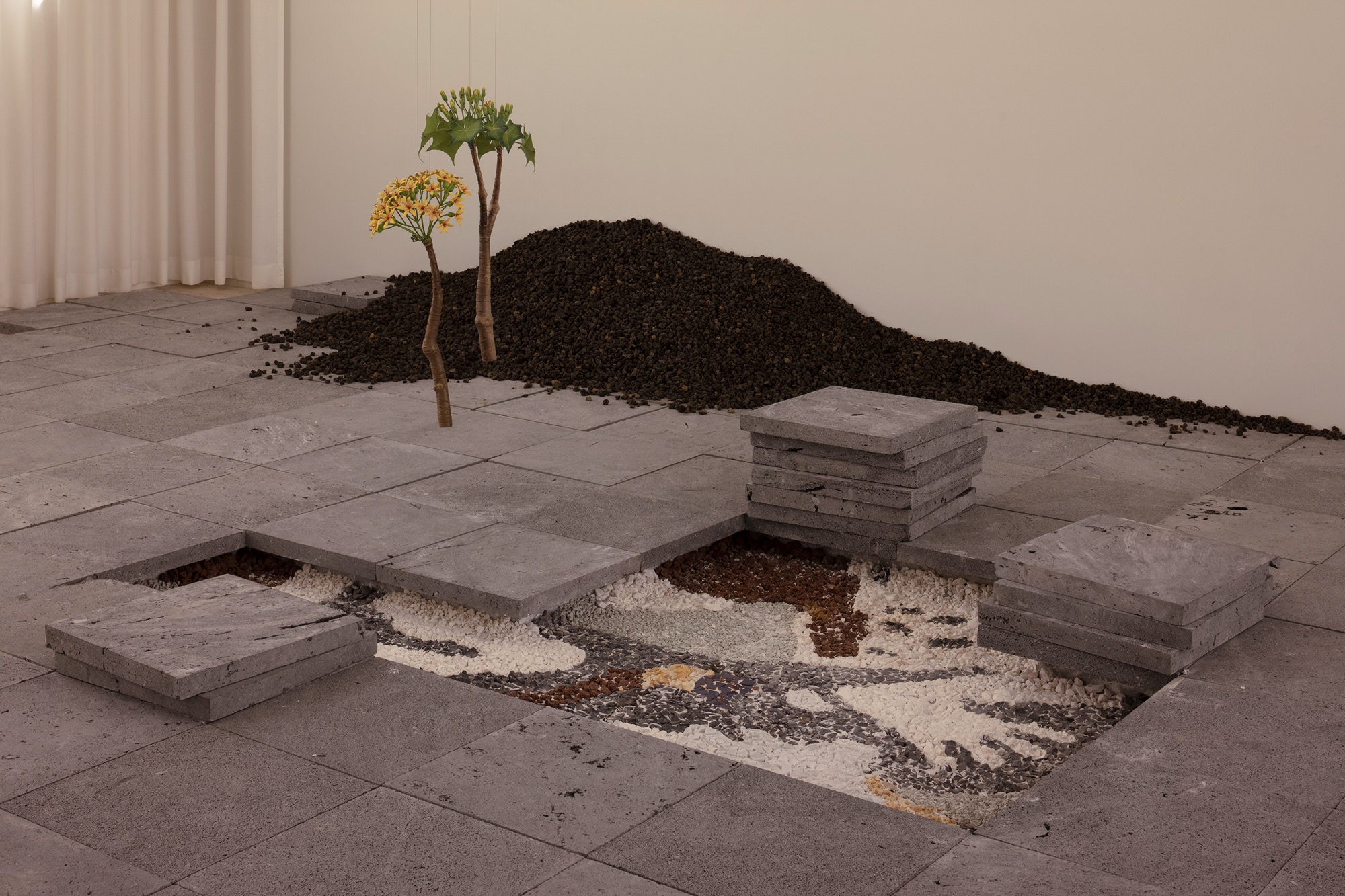 a site specific installation with loose stone and pavers and suspended florals