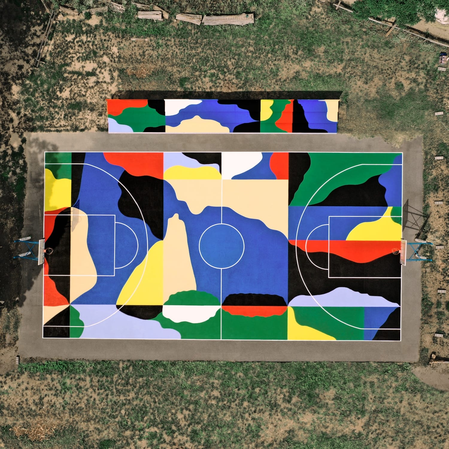an aerial view of a colorful, geometric abstract mural on a basketball court